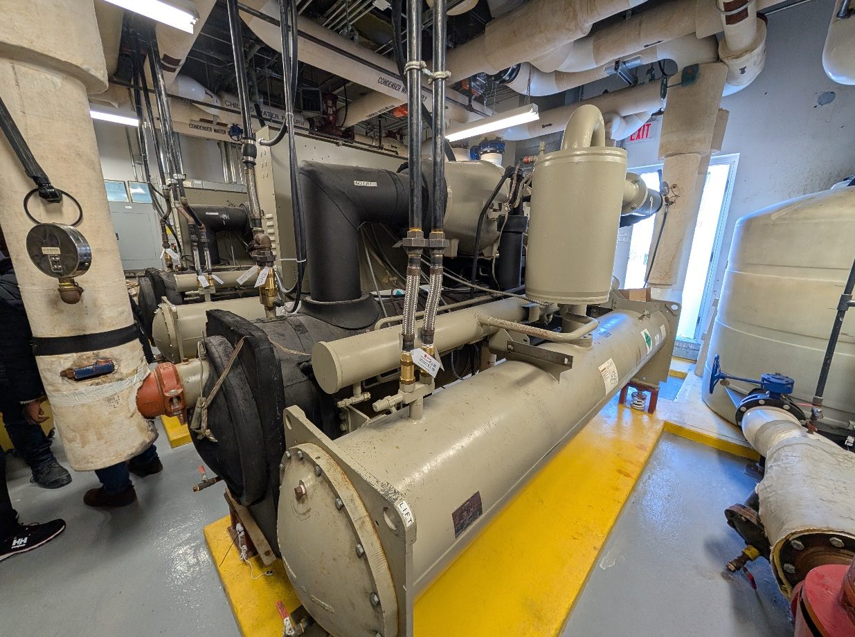 Two screw chillers in the penthouse mechanical room with insulated chilled and condenser water piping overhead