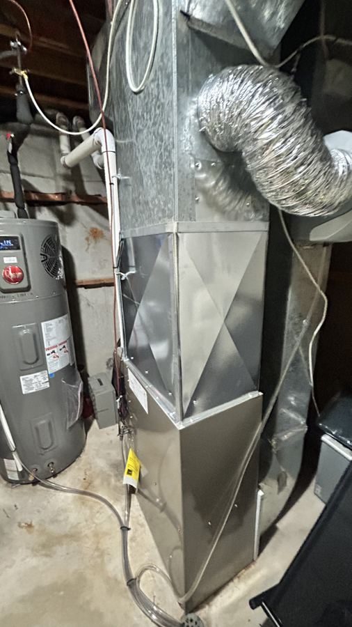 Completed townhome mechanical room: new heat pump water heater beside a new furnace and air handler, ducted and commissioned